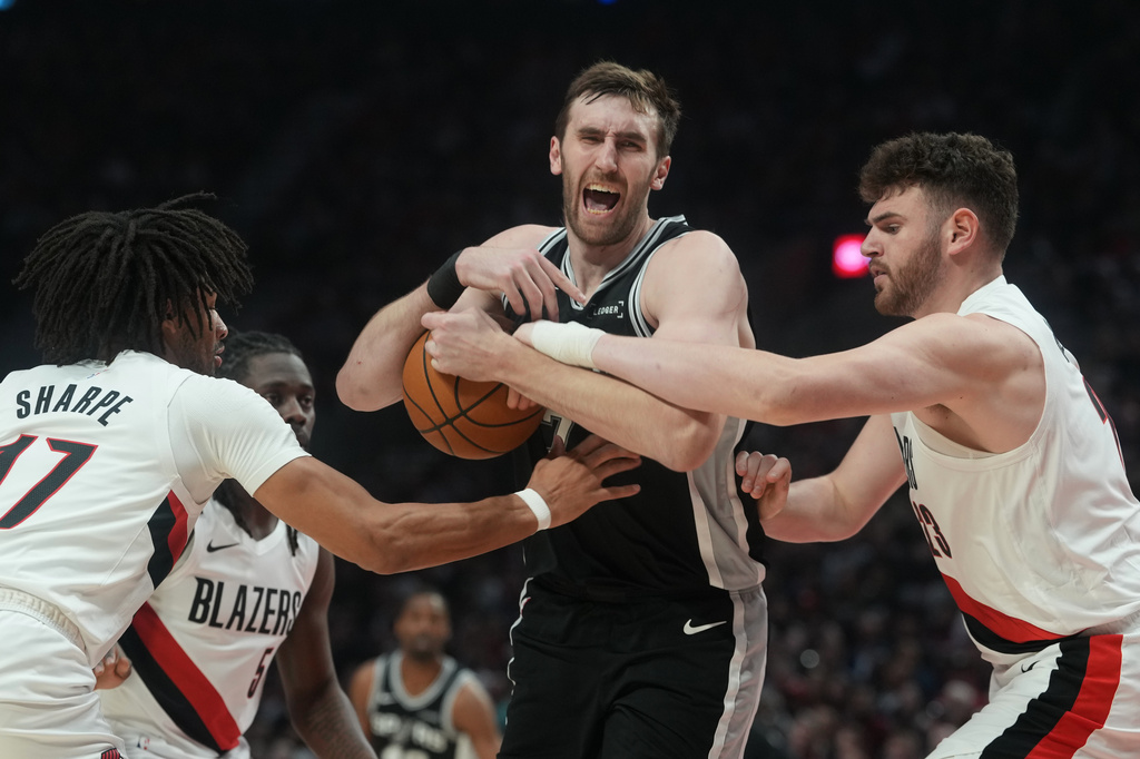 San Antonio Spurs center Luke Kornet, center, and Portland Trail Blazers center Donovan Clingan, right, battle for control of the ball during the second half in Game 3 of a first-round NBA playoffs basketball series in Portland, Ore, Friday, April 24, 2026. (AP Photo/Jenny Kane)