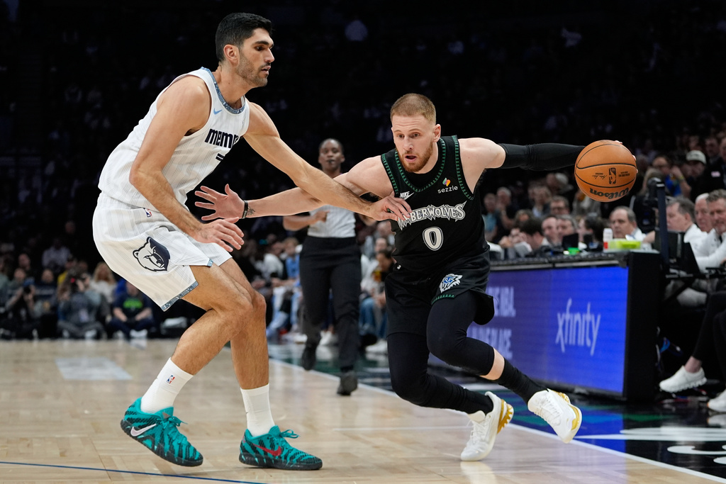 Minnesota Timberwolves guard Donte Divincenzo (0) works toward the basket as Memphis Grizzlies forward Santi Aldama (7) defends during the first half of an NBA basketball game, Wednesday, Dec. 17, 2025, in Minneapolis. (AP Photo/Abbie Parr)