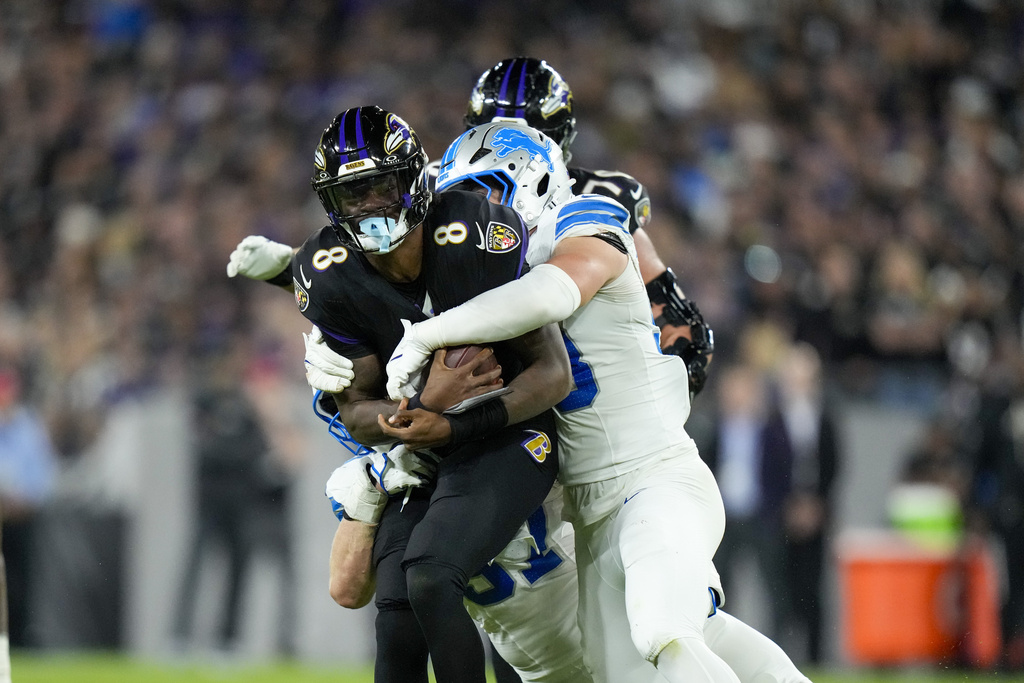 Baltimore Ravens quarterback Lamar Jackson (8) is brought down by Detroit Lions linebacker Trevor Nowaske, right, and defensive end Aidan Hutchinson, bottom, during the second half of an NFL football game Monday, Sept. 22, 2025, in Baltimore. (AP Photo/Stephanie Scarbrough)