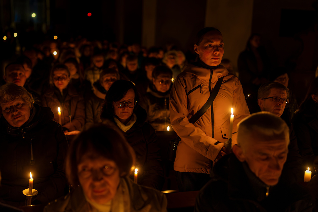 Worshippers hold candles during the Easter vigil Mass in the Cathedral Basilica of Vilnius, Lithuania, late Saturday, April 4, 2026. (AP Photo/Mindaugas Kulbis)