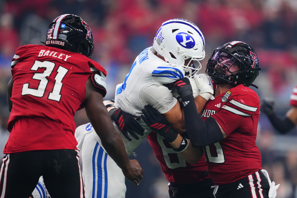BYU running back LJ Martin (4) is stopped as he runs the ball by Texas Tech defensive lineman E'Maurion Banks (8) and linebacker Jacob Rodriguez (10) as David Bailey (31) looks on in the second half of a Big 12 Conference championship NCAA college football game Saturday, Dec. 6, 2025, in Arlington, Texas. (AP Photo/Julio Cortez)