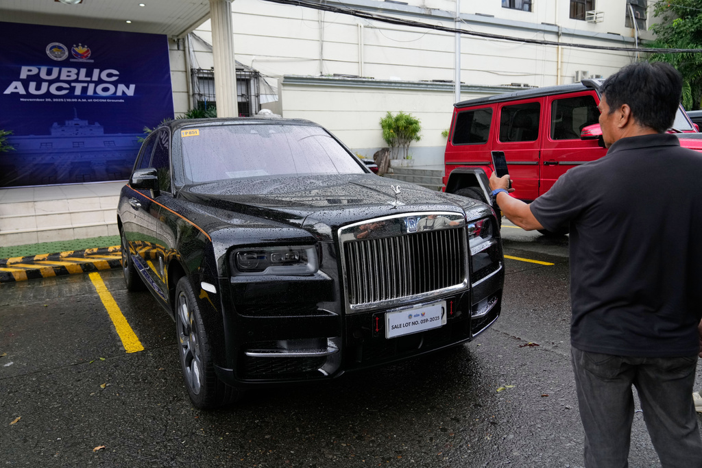 A man takes a picture of a Rolls-Royce luxury vehicle that is auctioned after it was seized from a wealthy couple accused in massive flood-control project corruptions at the Bureau of Customs in Manila, Philippines on Thursday, Nov. 20, 2025. (AP Photo/Aaron Favila)