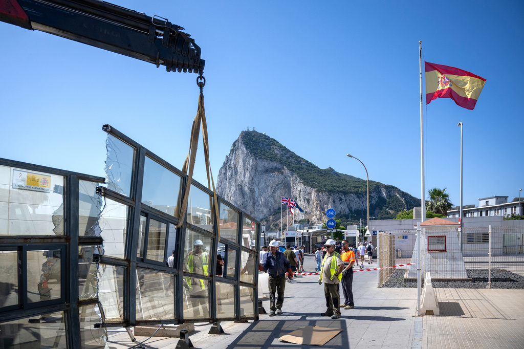 Against the backdrop of the Rock of Gibraltar, workers dismantle a Spanish border checkpoint that separated the disputed British overseas territory from Spain in La Línea de la Concepción, Spain, Monday, July 6, 2026. (AP Photo/Marcos Moreno)