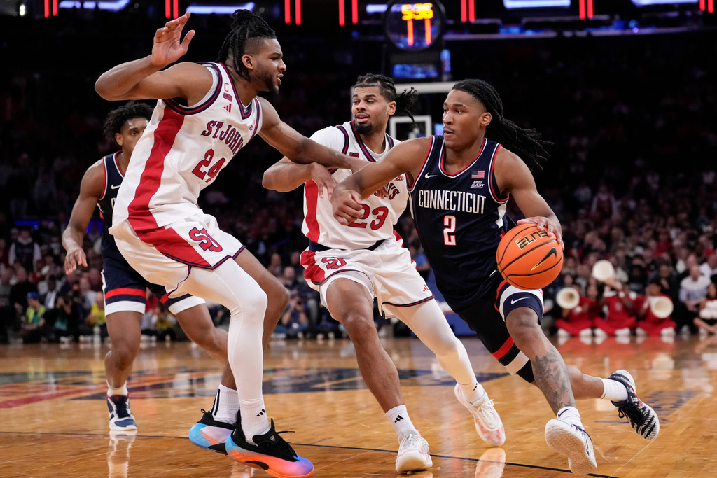 UConn guard Silas Demary Jr. (2) drives past St. John's forward Zuby Ejiofor (24) and St. John's forward Bryce Hopkins (23) during the second half of an NCAA college basketball game in the championship of the Big East tournament, Saturday, March 14, 2026, in New York. (AP Photo/Yuki Iwamura)