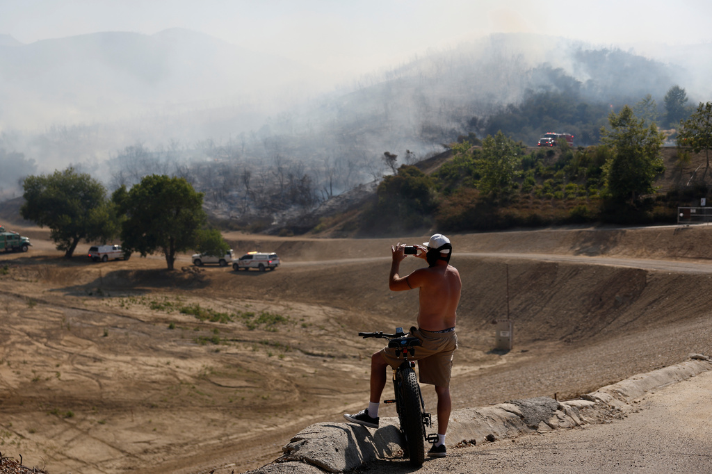 A resident uses a smartphone as the Sandy Fire approaches, Tuesday, May 19, 2026, in Simi Valley, Calif. (AP Photo/Caroline Brehman)