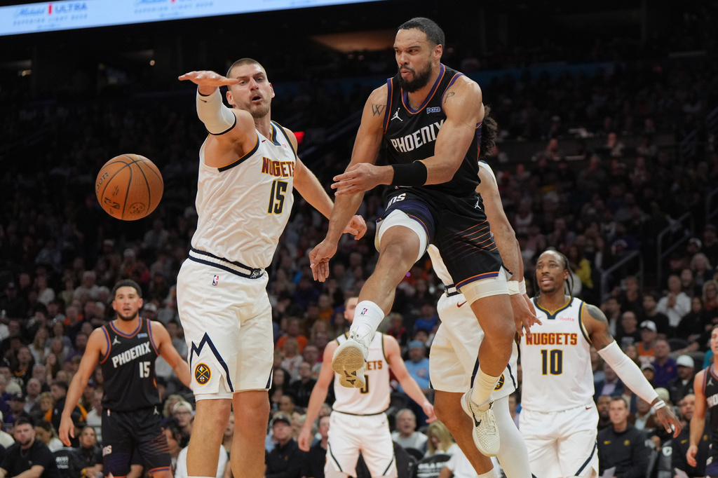 Phoenix Suns forward Dillon Brooks, front right, passes the ball around Denver Nuggets center Nikola Jokic (15) during the first half of an NBA Cup basketball game, Friday, Oct 30, 2026, in Phoenix. (AP Photo/Rick Scuteri)