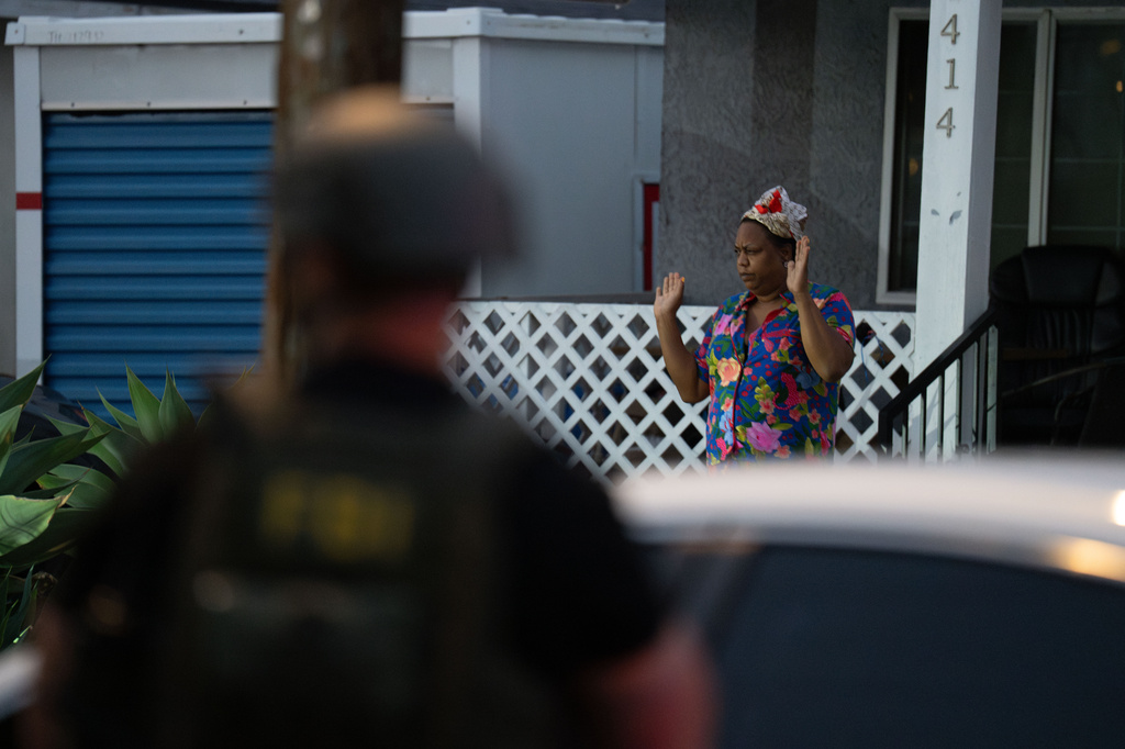 Lakiya Malone, charged with fraud involving federal homelessness aid programs, walks out of her home toward federal authorities with her hand raised in Los Angeles, Wednesday, Sept. 16, 2026. (AP Photo/Jae C. Hong)