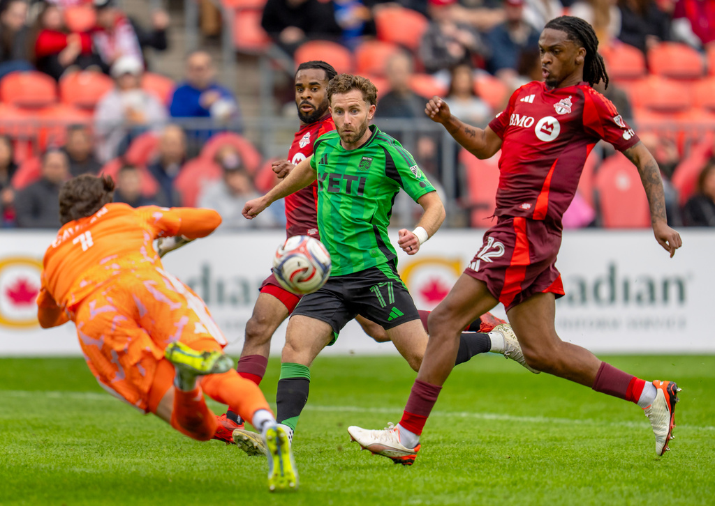 Toronto FC's goalkeeper Luka Gavran (1) dives to make a save on Austin FC's Jon Gallagher (17) as Toronto FC's Zane Monlouis (12) joins the fray during the first half of an MLS soccer game in Toronto, Saturday, April 18, 2026. (Frank Gunn/The Canadian Press via AP)