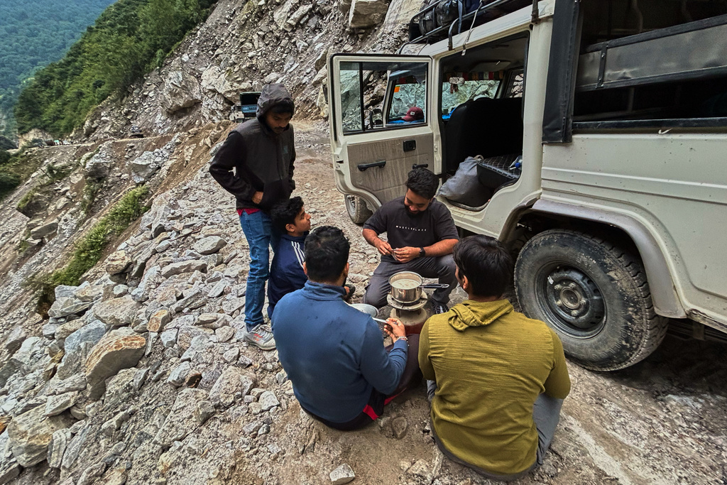 Travelers make tea as they wait for a mountain road to be cleared of debris near Laspa village, in the northern Indian Himalayan state of Uttarakhand, on Oct. 4, 2025. (AP Photo/Satish Sharma)