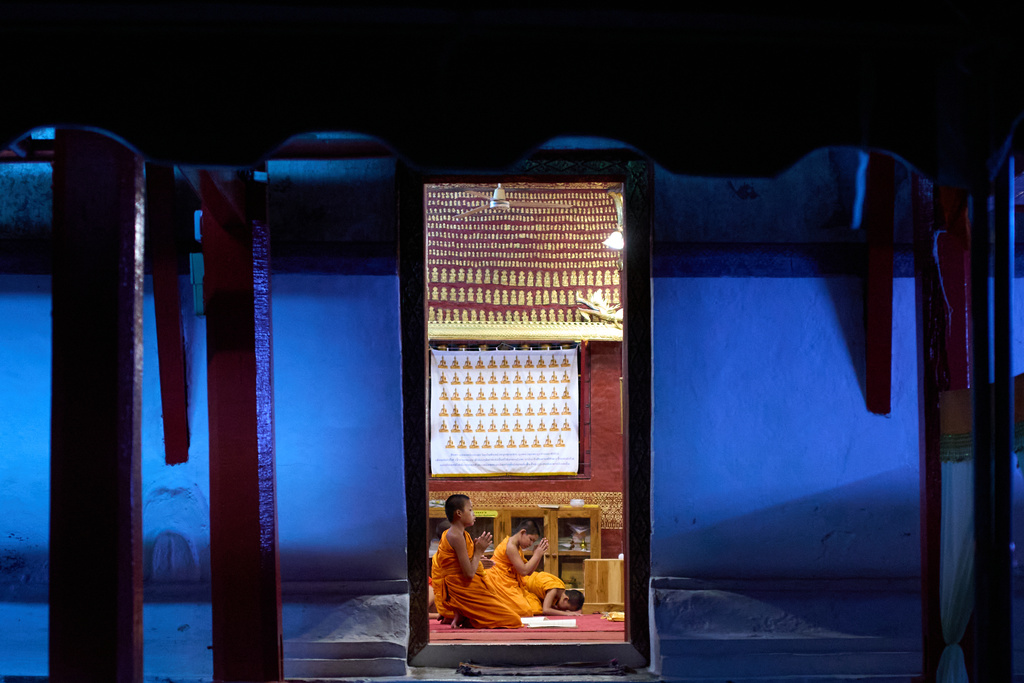 Novice Buddhist monks pray inside a temple as evening light fades outside in Luang Prabang, Laos, Sunday, Nov. 2, 2025. (AP Photo/Eugene Hoshiko)