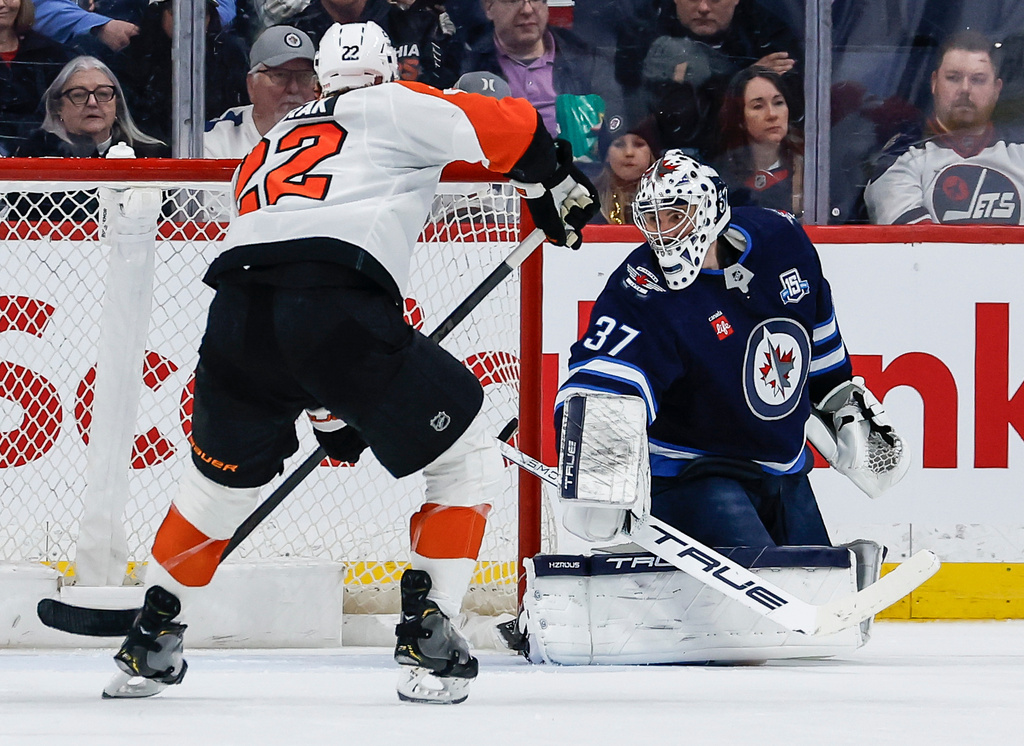 Winnipeg Jets goaltender Connor Hellebuyck (37) is scored on as Philadelphia Flyers' Christian Dvorak (22) looks on during second period NHL action in Winnipeg, Saturday, April 11, 2026. (John Woods/The Canadian Press via AP)