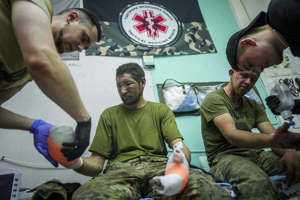Ukrainian medics of Da Vinci Wolves Battalion treat their injured comrades at a stabilisation point on Pokrovsk direction, Ukraine, Sunday, Aug. 10, 2025. (AP Photo/Evgeniy Maloletka)