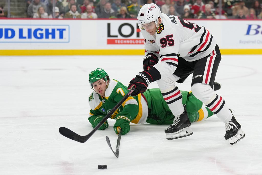 Chicago Blackhawks right wing Ilya Mikheyev (95) and Minnesota Wild defenseman Brock Faber (7) reach for the puck during the second period of an NHL hockey game, Tuesday, Jan. 27, 2026, in St. Paul, Minn. (AP Photo/Abbie Parr)