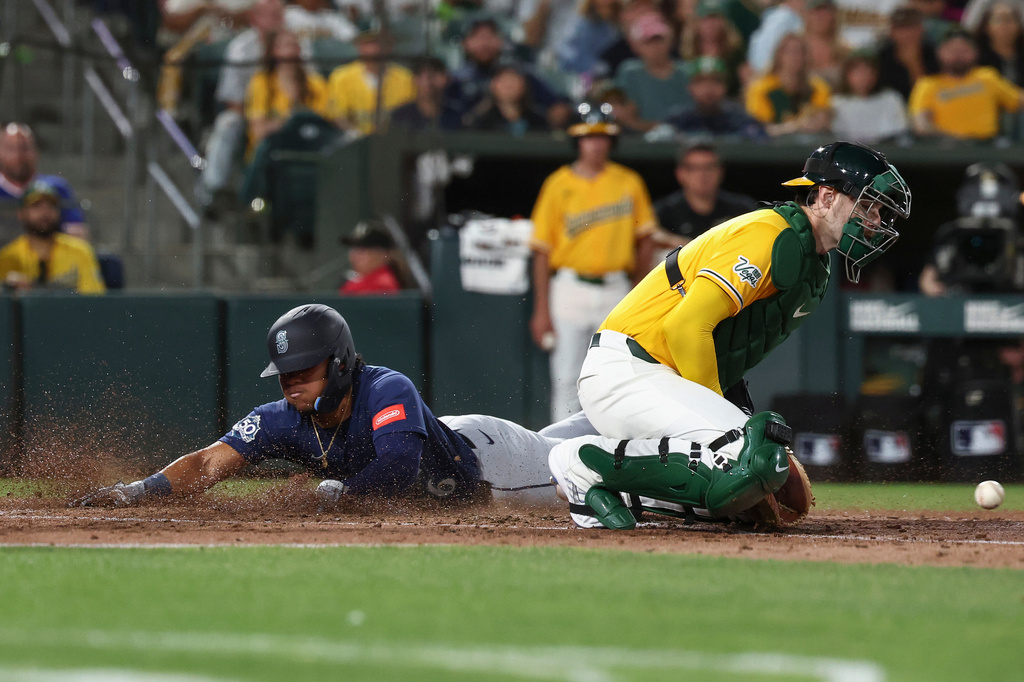 Athletics catcher Jonah Heim, right, attempts to put out Seattle Mariners' Michael Arroyo, left, at home during the fourth inning of a baseball game Saturday, Sept. 12, 2026, in West Sacramento, Calif. (AP Photo/Sara Nevis)