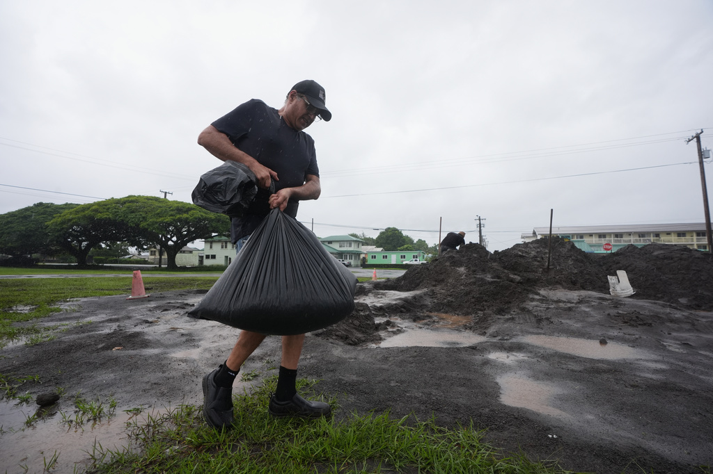 Darren Montalvo carries sand bags he will use to help keep water out of his restaurant as Hurricane Nolo approaches in Hilo, Hawaii, Friday, Sept. 25, 2026. (AP Photo/Gregory Bull)