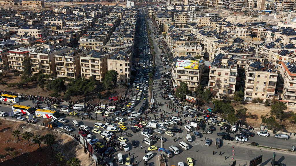 An aerial view shows Syrian residents in vehicles, queueing to flee from Sheikh Maqsoud and Achrafieh neighborhoods after clashes broke out on Tuesday between Syrian government forces and Kurdish fighters in a contested area of the northern city of Aleppo, Syria, Wednesday, Jan. 7, 2026. (AP Photo/Omar Albam)