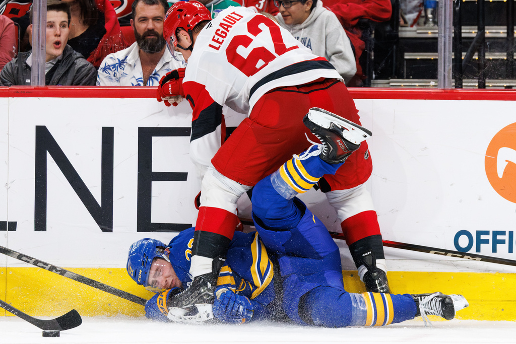 Buffalo Sabres Jack Quinn is knocked to the ice by Carolina Hurricanes Charles Alexis Legault (62) during the third period of an NHL hockey game in Raleigh, N.C., Saturday, Nov. 8, 2025. (AP Photo/Ben McKeown)