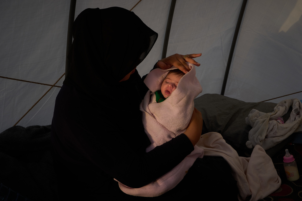 Haifa Kenjo, who fled Israeli airstrikes on the southern suburbs of Beirut, holds her 15-day-old daughter Shiman inside the tent she uses as a shelter and where she gave birth to her in Beirut, Sunday, April 12, 2026. (AP Photo/Emilio Morenatti)