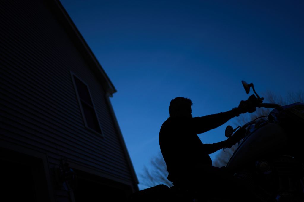 Chris Colocousis, whose retirement savings were stolen by a scammer, starts up his motorcycle on a warm winter day outside his home in Raynham, Mass., Tuesday, March 10, 2026. (AP Photo/David Goldman)