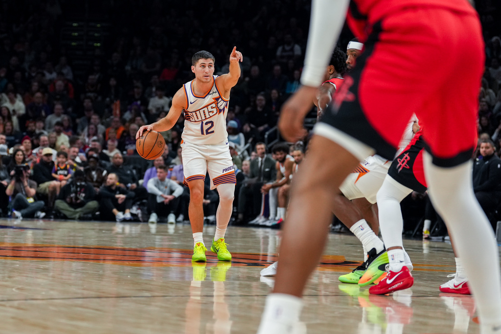 Phoenix Suns guard Collin Gillespie (12) signals to his team during the first half of an NBA basketball game against the Houston Rockets, Monday, Nov. 24, 2025, in Phoenix. (AP Photo/Samantha Chow)