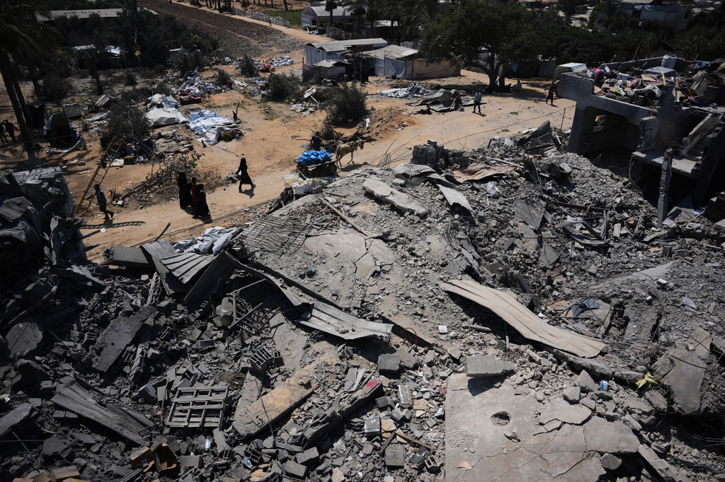 Palestinians walk past a food-aid warehouse damaged in an Israeli airstrike that targeted a nearby house in Deir al-Balah, central Gaza Strip, Wednesday, Aug. 26, 2026. (AP Photo/Abdel Kareem Hana)