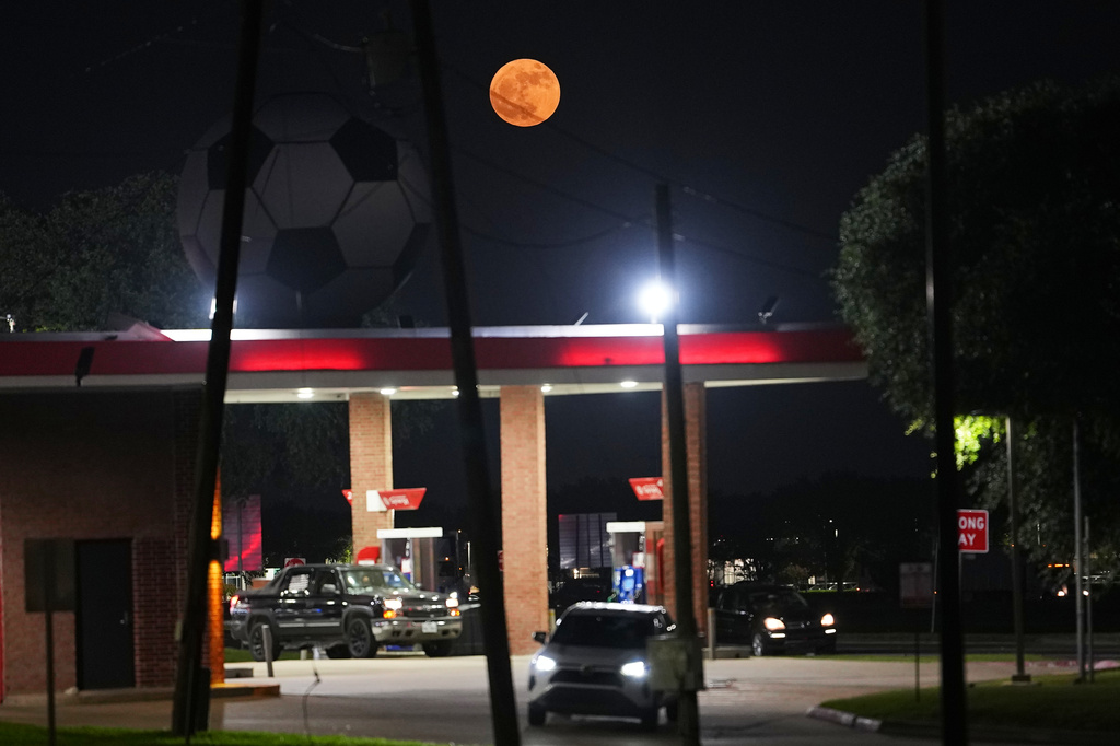 The full moon rises behind a large soccer ball atop a gas station in honor of the World Cup soccer tournament in Arlington, Texas, near Dallas, Monday, June 29, 2026. (AP Photo/Julio Cortez)
