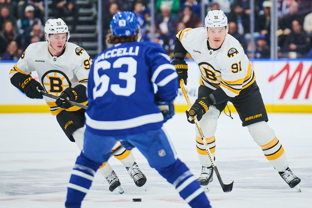 Boston Bruins' Fraser Minten (93) and teammate Nikita Zadorov (91) move with the puck as Toronto Maple Leafs' Matias Maccelli (63) defends during the first period of an NHL hockey game in Toronto on Saturday, Nov. 8, 2025. (Sammy Kogan/The Canadian Press via AP)