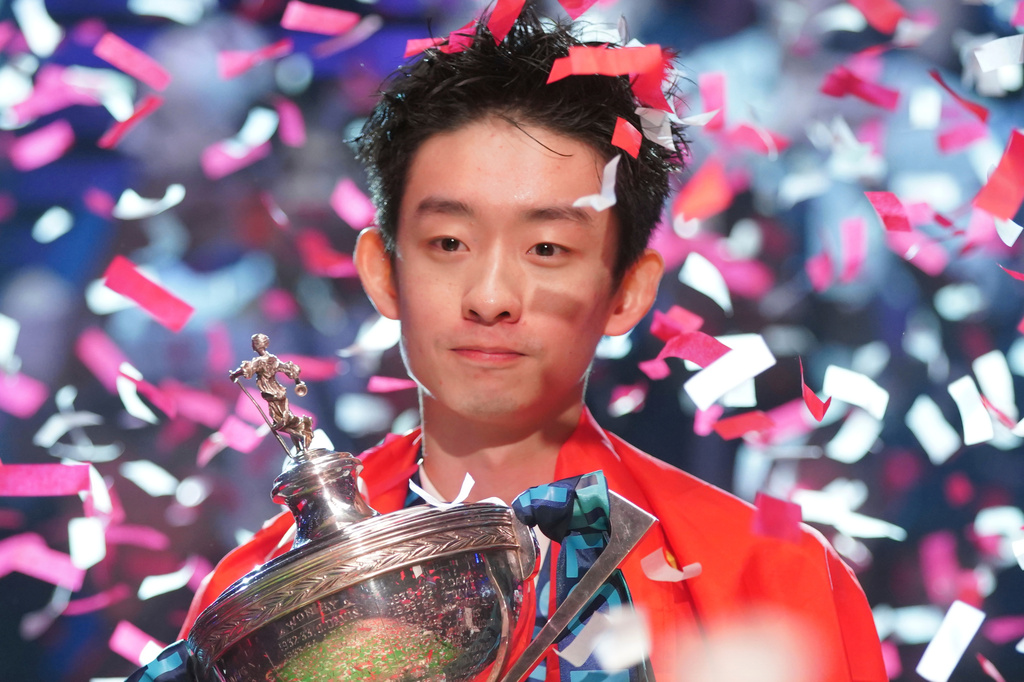 China's Wu Yize poses for the media with the trophy and wearing the Chinese national flag, after winning the World Snooker Championship defeating England's Shaun Murphy in Sheffield, England, Monday, May 4, 2026.(AP Photo/Ian Hodgson)