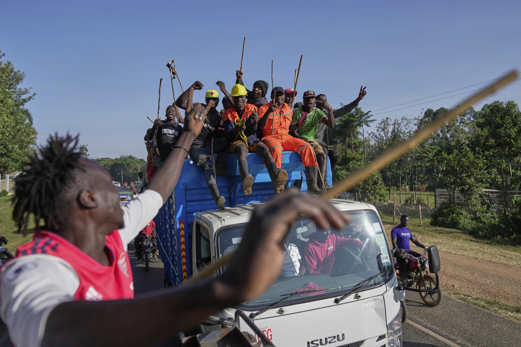 Spectators escort a truck where a bull is loaded, waving their chasing sticks and ululating, on the way to a bullfight in Kakamega, Kenya, Saturday, Nov. 29, 2025. (AP Photo/Brian Inganga)
