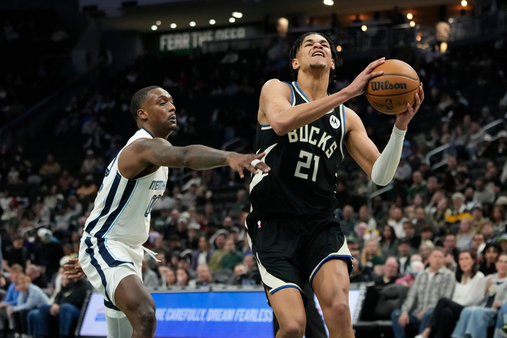 Milwaukee Bucks' Ousmane Dieng (21) drives to the basket past Memphis Grizzlies' Dariq Whitehead during the first half of an NBA basketball game, Sunday, April 5, 2026, in Milwaukee. (AP Photo/Aaron Gash)