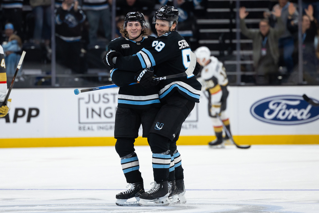 Utah Mammoth center Logan Cooley, left, and defenseman Mikhail Sergachev, right, celebrate after Cooley scored his third goal of the night during the third period of an NHL hockey game, Monday, Nov. 24, 2025, in Salt Lake City. (AP Photo/Anna Fuder)