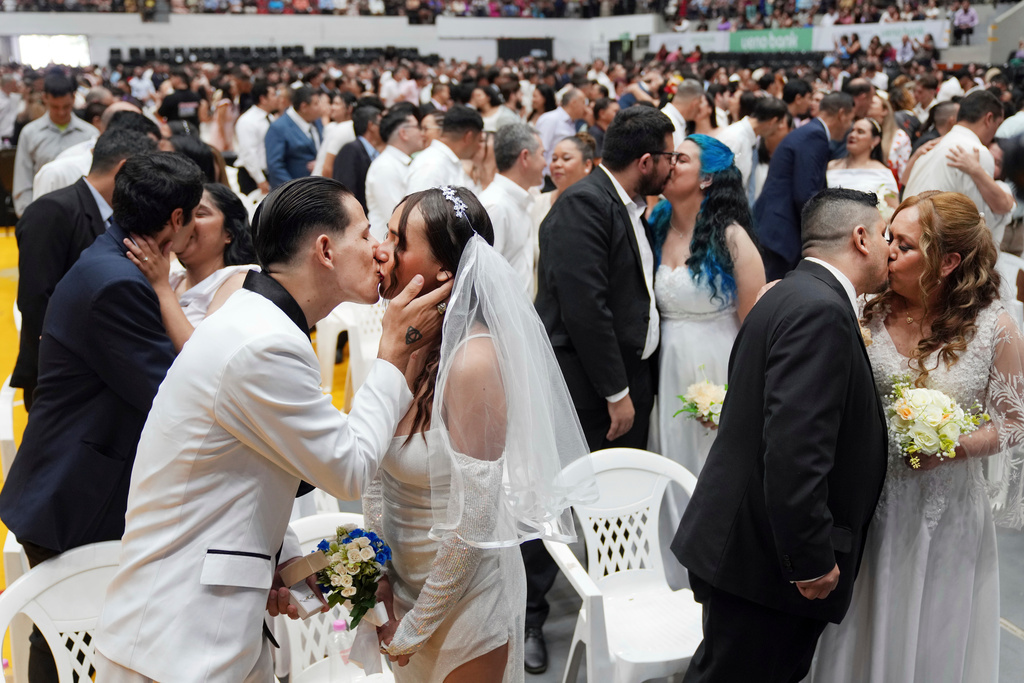 Jonathan Garay, left, kisses Fiorella Riveros during a group wedding ceremony organized by the Civil Registry to legally formalize their unions in in Asuncion, Paraguay, Saturday, Oct. 4, 2025. (AP Photo/Jorge Saenz)