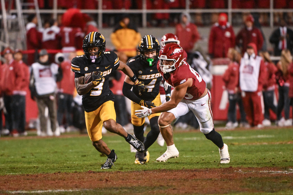 Missouri wide receiver Kevin Coleman Jr. (3) slips past Arkansas tight end Rohan Jones, right, to score a touchdown on a punt return during the second half of an NCAA college football game Saturday, Nov. 29, 2025, in Fayetteville, Ark. (AP Photo/Michael Woods)