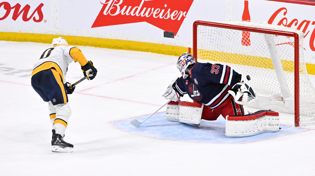 Nashville Predators' Ryan O'Reilly (90) scores on Winnipeg Jets goaltender Connor Hellebuyck (37) during the shootout of their NHL hockey game in Winnipeg, Tuesday March 17, 2026. (Fred Greenslade/The Canadian Press via AP)