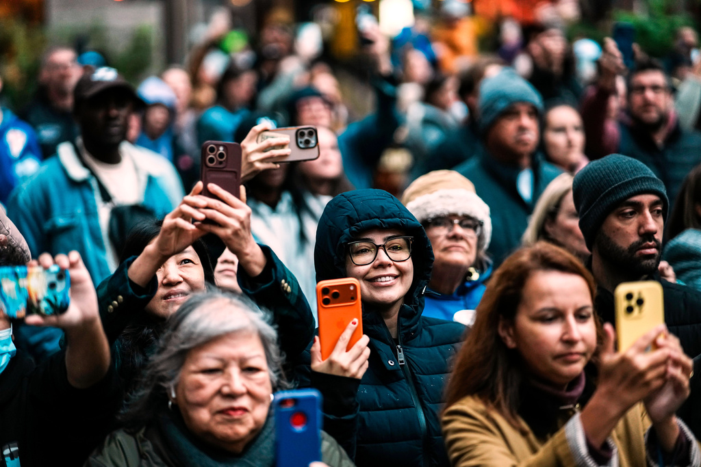 People view the Rockefeller Center Christmas tree while it's lifted by a crane into place at Rockefeller Plaza, Saturday, Nov. 8, 2025, in New York. (AP Photo/Eduardo Munoz Alvarez)