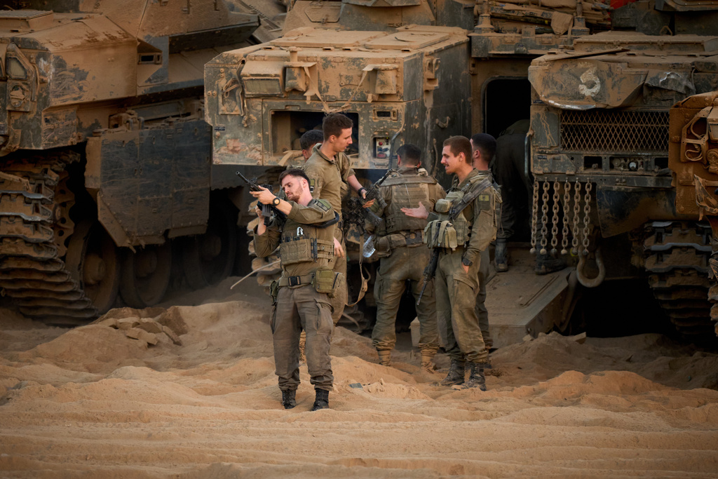 Israeli soldiers stand near their tanks along the Israeli-Gaza border, as seen from southern Israel, Friday, Oct. 10, 2025, after Israel and Hamas have agreed to a pause in their war and the release of the remaining hostages. (AP Photo/Emilio Morenatti)
