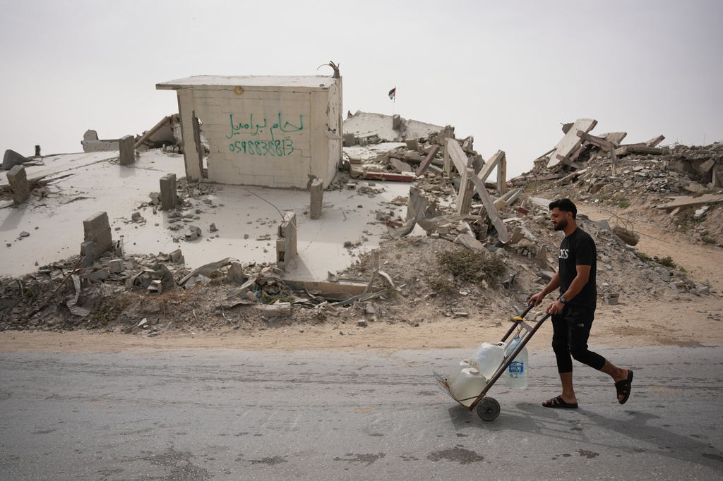 A Palestinian man carries water containers in Gaza City, Tuesday, May 12, 2026. (AP Photo/Abdel Kareem Hana)
