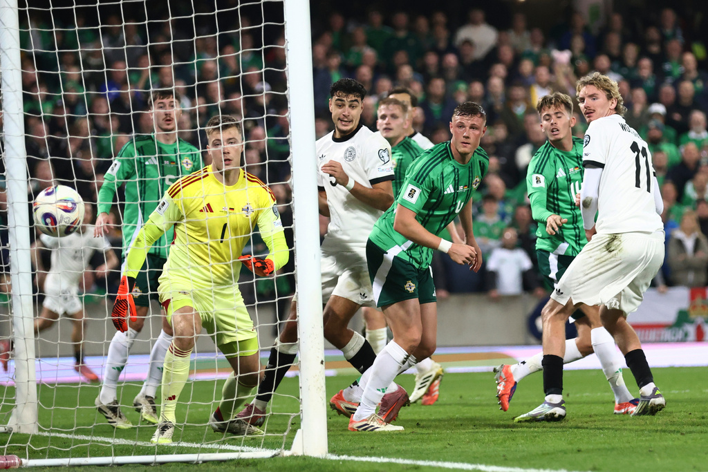 Germany's Nick Woltemade, right, scores the opening goal of his team as Northern Ireland's goalkeeper Bailey Peacock-Farrell watches the ball during the World Cup 2026 group A qualifying soccer match between Northern Ireland and Germany at Windsor Park stadium, in Belfast, Northern Ireland, Monday, Oct. 13, 2025. (AP Photo/Peter Morrison)