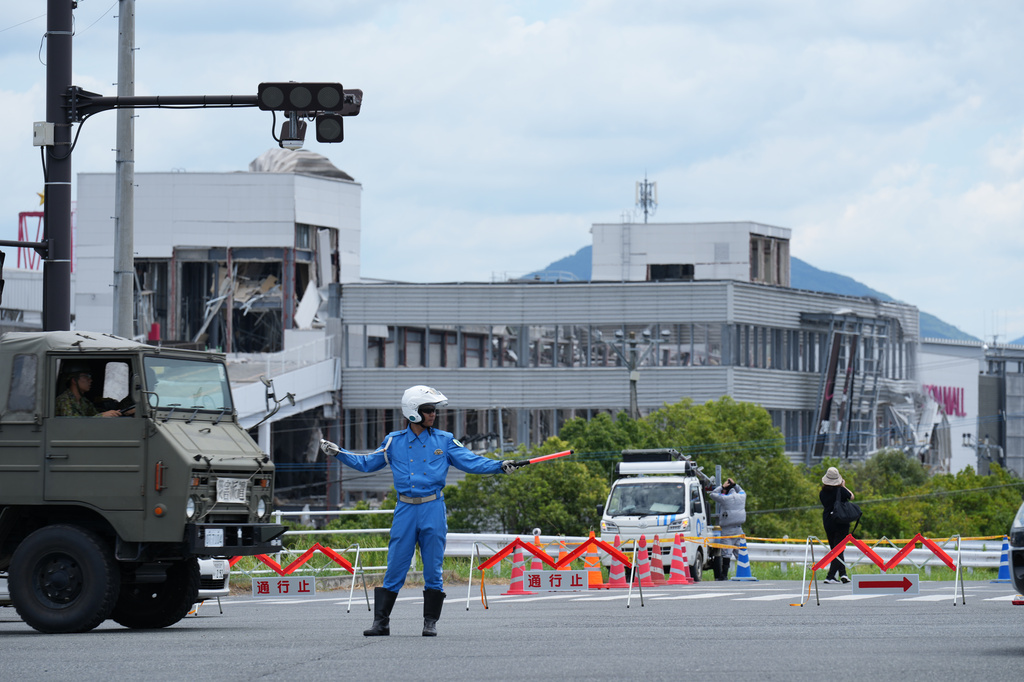 A police officer controls the traffic near AEON Mall, which was destroyed by an explosion following an earthquake, in Kashima, Kumamoto Prefecture, southern Japan, Wednesday, July 29, 2026. (AP Photo/Hiro Komae)
