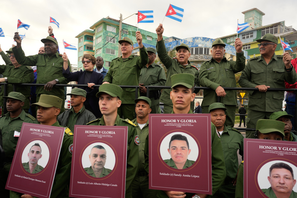 Cuban President Miguel Diaz-Canel, fourth from right, holds up a Cuban flag during a rally to protest the killing of Cuban officers during the U.S. operation that captured Venezuelan President Nicolas Maduro, outside the U.S. Embassy in Havana, Cuba, Friday, Jan. 16, 2026. (AP Photo/Ramon Espinosa)