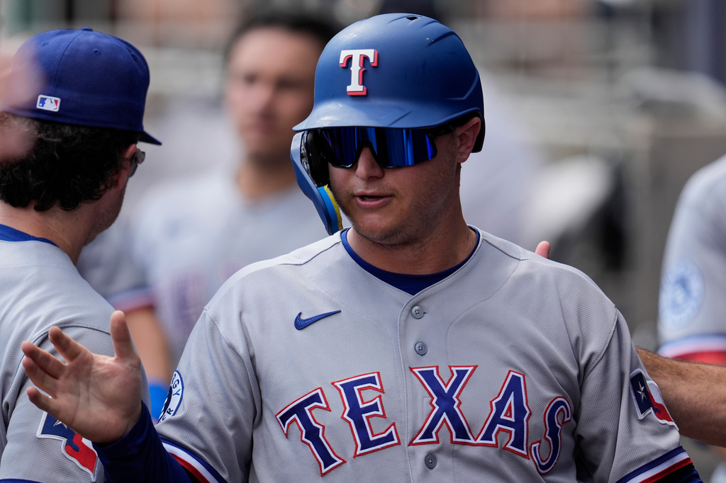 Texas Rangers designated hitter Joc Pederson (3) celebrates scoring off the bat of Brandon Nimmo in the third inning of a baseball game against the Atlanta Braves, Saturday, July 18, 2026, in Atlanta. (AP Photo/Mike Stewart)