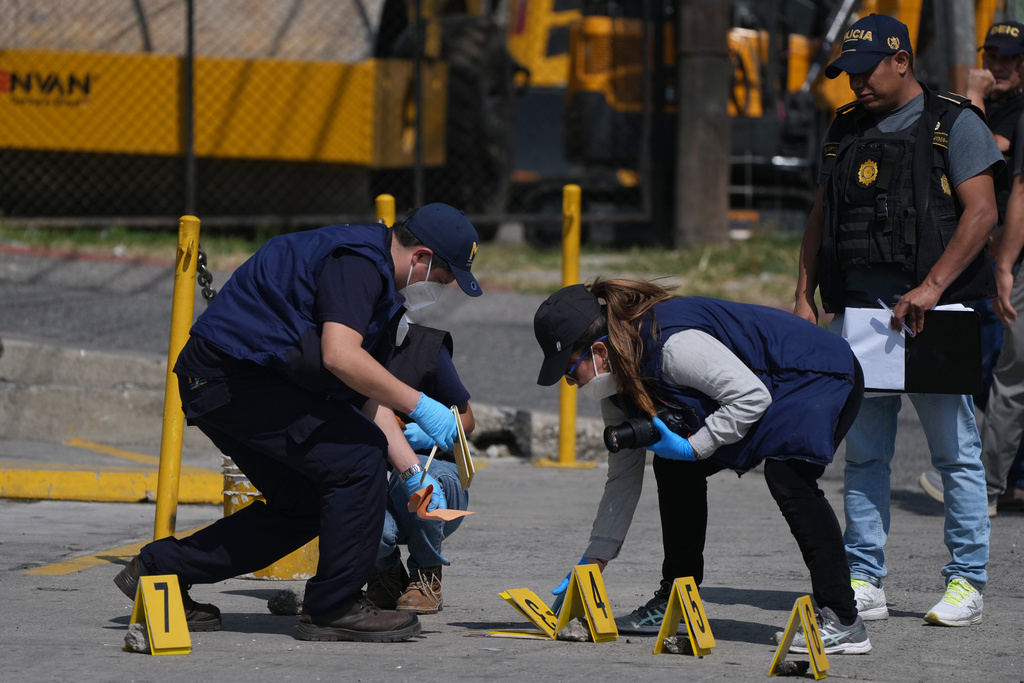 Forensic investigators place evidence markers at the scene where police officers were killed in attacks reported after security forces retook control of a prison that houses gang leaders, in Villanueva, outskirts of Guatemala City, Sunday, Jan. 18, 2026. (AP Photo/Moises Castillo)