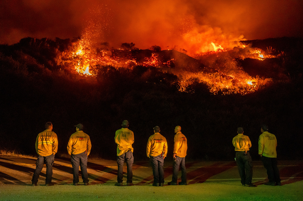 Firefighters watch as a wildfire called the Plaskett Fire burns towards Highway 1 on Friday, Aug. 28, 2026, in Big Sur, Calif. (AP Photo/Ethan Swope)