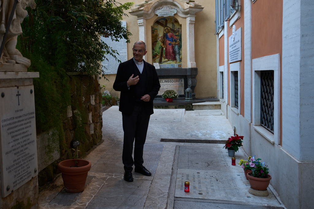 Mons. Peter Klasvogt, the rector of the Teutonic College poses for a photo next to the tomb of Burkhard Scheffler, a homeless man who died from the cold in 2022 on the edge of St. Peter's Square, and portrayed as St. Peter in a painting by German artist Michael Triegel, exposed in the chapel of the Teutonic College at the Vatican, Wednesday, Dec. 10, 2025. (AP Photo/Alessandra Tarantino)