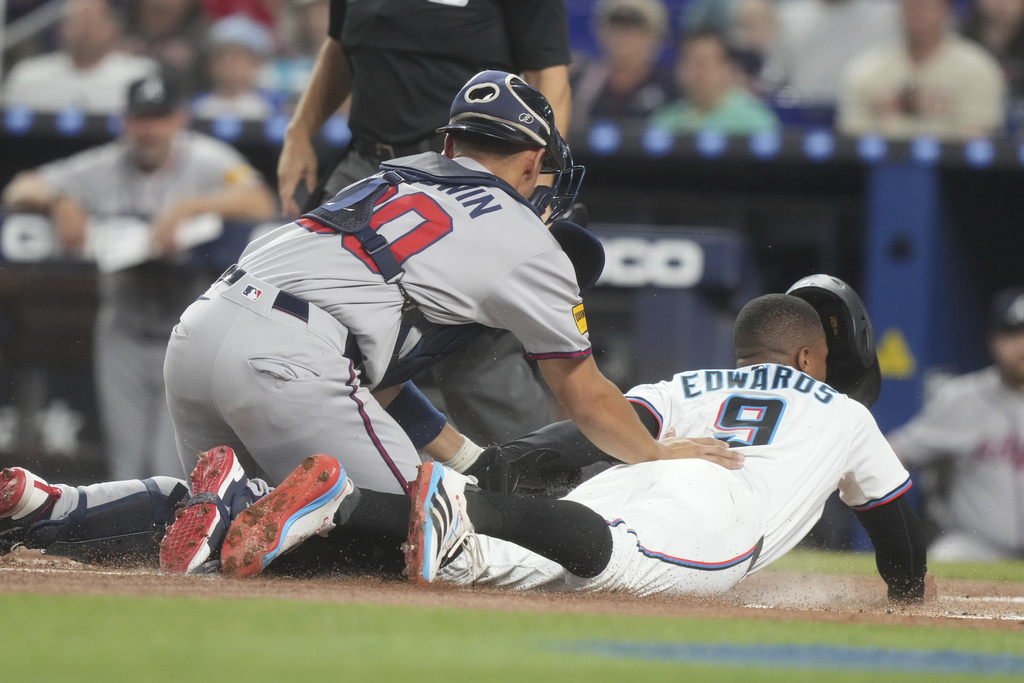 Atlanta Braves catcher Drake Baldwin (30) tags Miami Marlins' Xavier Edwards (9) out at home plate during the first inning of a baseball game, Monday, Aug. 25, 2025, in Miami. (AP Photo/Marta Lavandier)