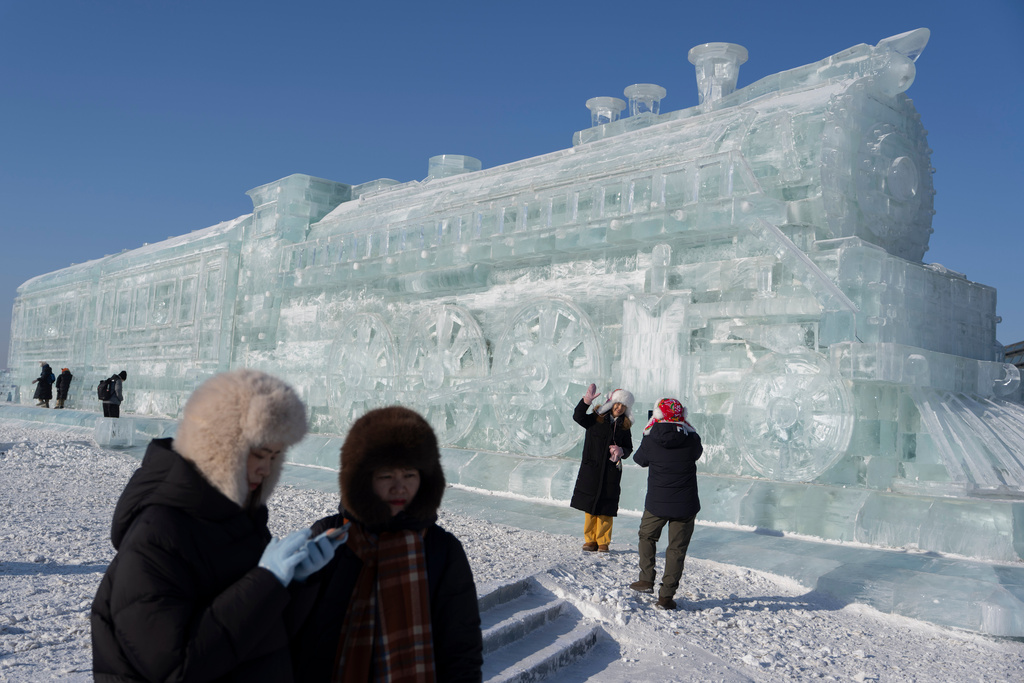 Visitors stand near a giant ice sculpture of a train at the annual Ice and Snow Festival held in Harbin in China's Heilongjiang province on Sunday, Jan. 4, 2026. (AP Photo/Ng Han Guan)