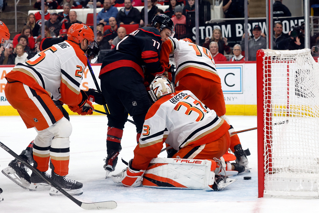 Carolina Hurricanes' Mark Jankowski (77) slips the puck past Anaheim Ducks goaltender Ville Husso (33) with Ducks' Ryan Poehling (25) and Drew Helleson (14) nearby during the second period of an NHL hockey game in Raleigh, N.C., Thursday, Jan. 8, 2026. (AP Photo/Karl DeBlaker)
