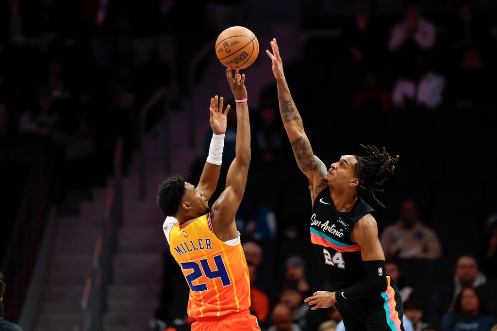 Charlotte Hornets forward Brandon Miller, left, shoots against San Antonio Spurs guard Devin Vassell during the first half of an NBA basketball game in Charlotte, N.C., Saturday, Jan. 31, 2026. (AP Photo/Nell Redmond)