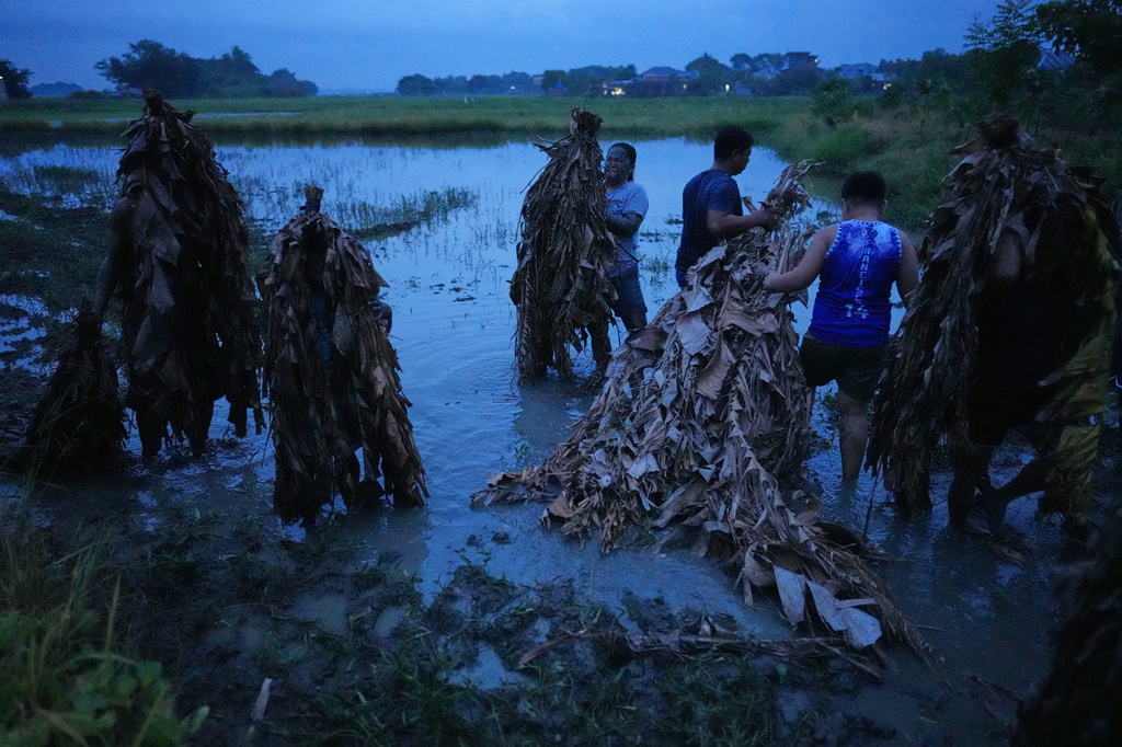 Catholic devotee Mika Castillo, center, and her family members cover themselves with mud at a rice field to participate in the mud people festival on the feast day of Saint John the Baptist at Bibiclat, Nueva Ecija province, northern Philippines on Wednesday, June 24, 2026. (AP Photo/Aaron Favila)