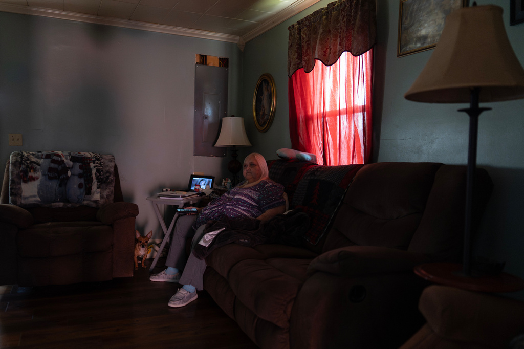 Rebecca Michalski, who recently took out a loan to pay her electric bills, sits with her Chihuahua named Enos in the dark in her home in Rainelle, W.Va., Saturday, March 21, 2026. (AP Photo/Carolyn Kaster)